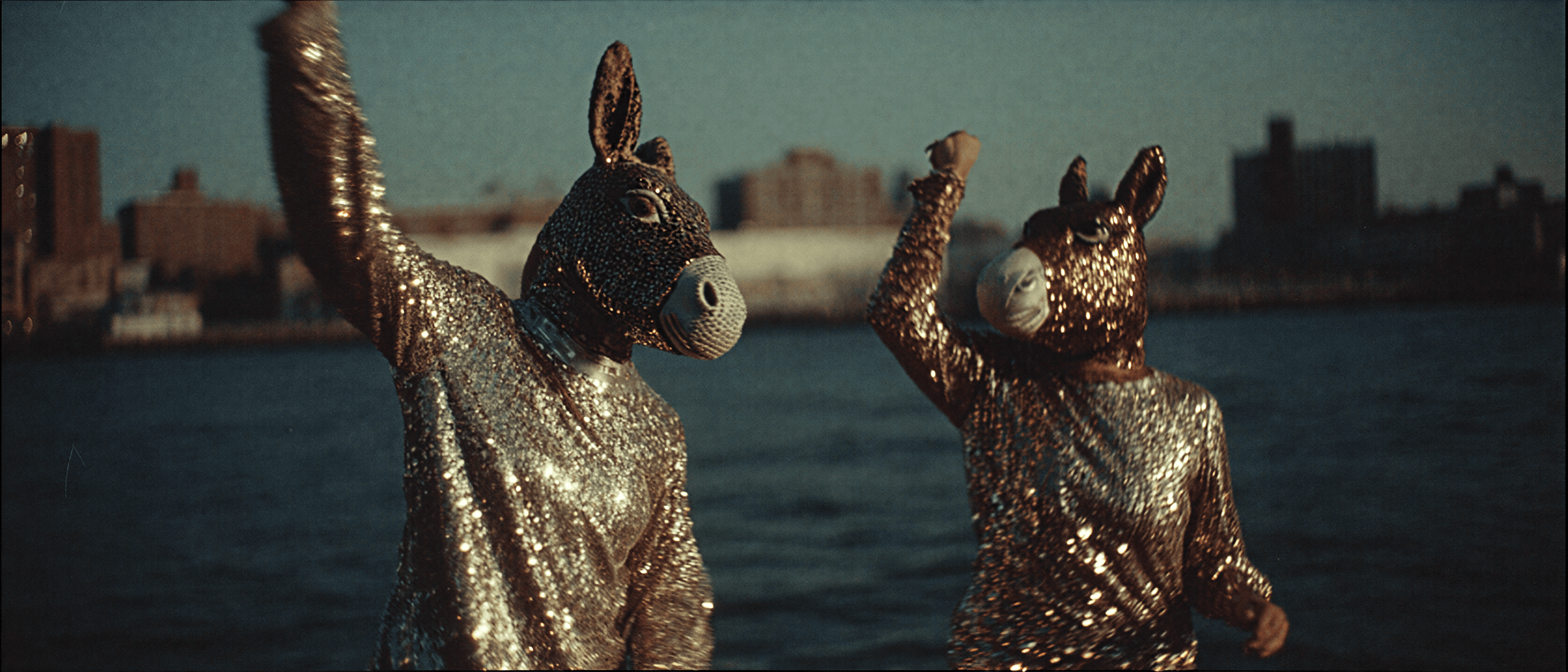 Two donkey-headed figures in 1970s sequin dresses on a dance floor