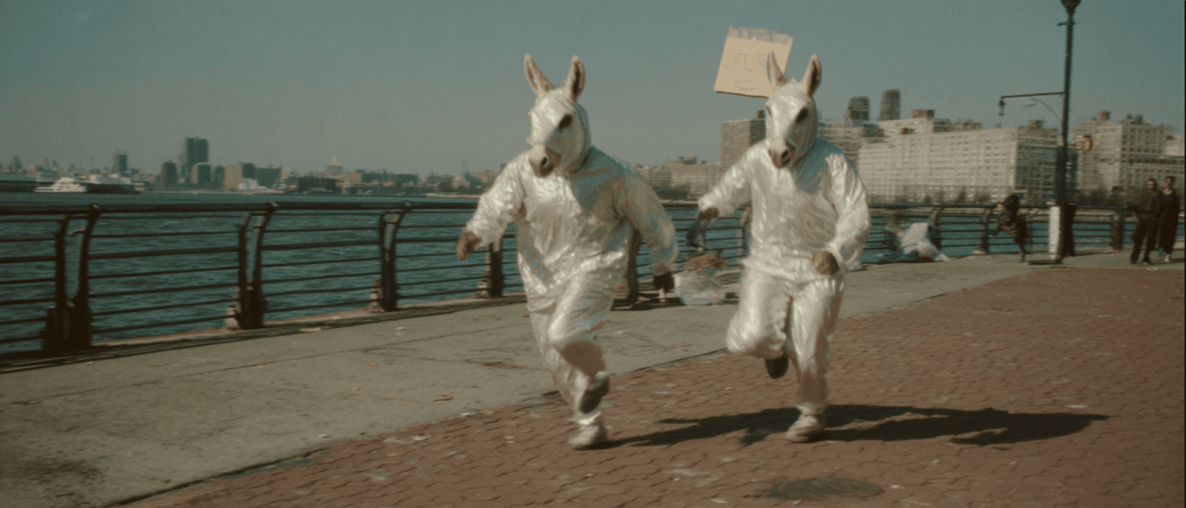 Donkey-headed figures running along a Brooklyn waterfront